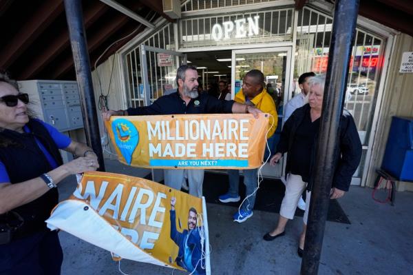 Lottery officials put up banners outside the entrance at the Midway Market & Liquor store, Thursday, Oct. 12, 2023, in Frazier Park, Calif.