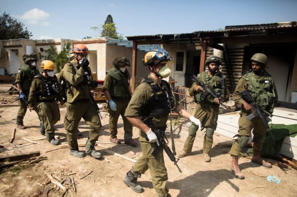 Israeli soldiers patrol burned out kibbutz.