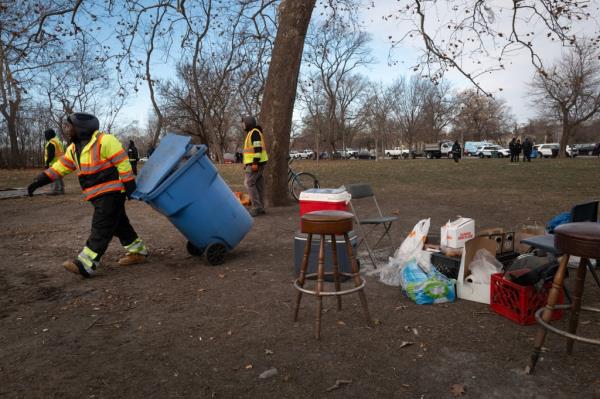 A tent getting dismantled by city workers.