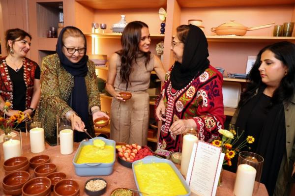 Meghan, Duchess of Sussex, hosting a holiday dinner for the Southern California Welcome Project through the Sussexes' Archewell Foundation surrounded by a group of women at a table filled with food in Venice, California.