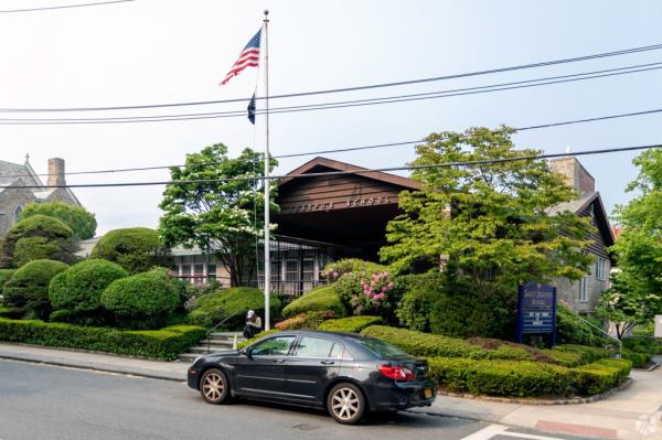 A car parked outside the St. Joseph School in Bronxville, flags seen in front and church in background.