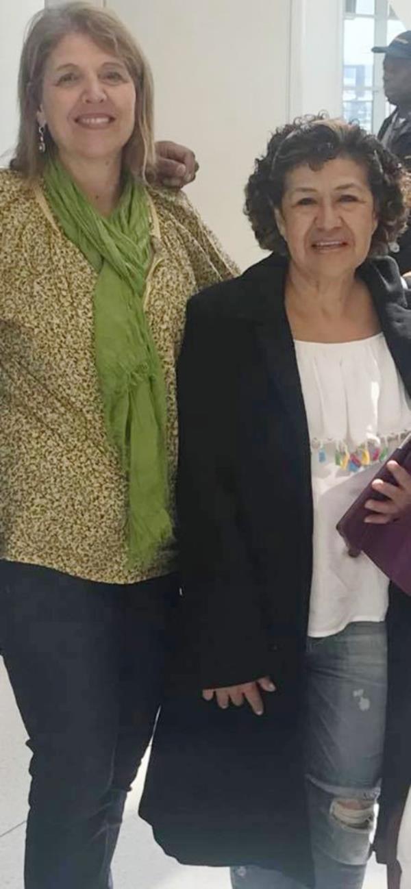 Former principal Mary Ellen Sanchez seen posing with another woman in a Facebook photo. Sanchez seen wearing green printed shirt and green scarf and woman in white shirt and dark blazer.