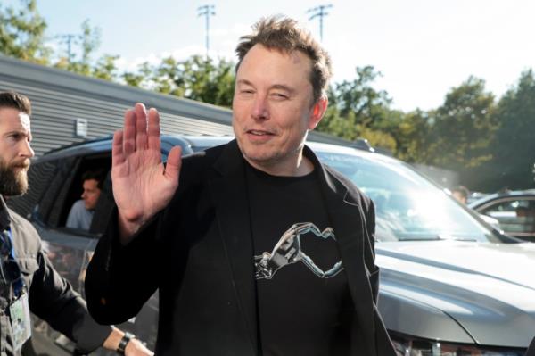 Elon Musk waving to cameras at US tennis championships.