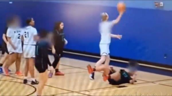 A player who identifies as transgender rips the ball from a female opponent, who falls to the floor.