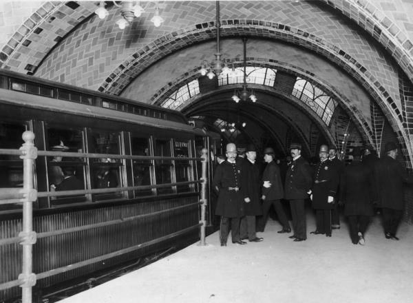 This 1904 photo shows police officers and other officials on the City Hall subway station platform as a train passes them.