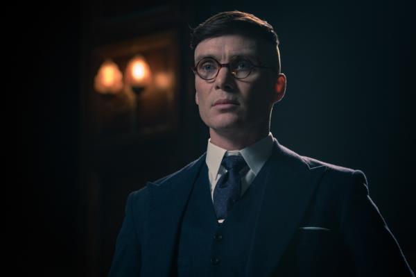 Cillian Murphy as Tommy Shelby in a later season when he was voted into Parliament. He's wearing a blue 1930s-style and horned-rimmed glasses.