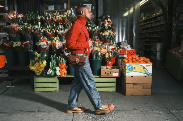 CJ Robinson walking in a red sweater and carrying brown shoulder bag 