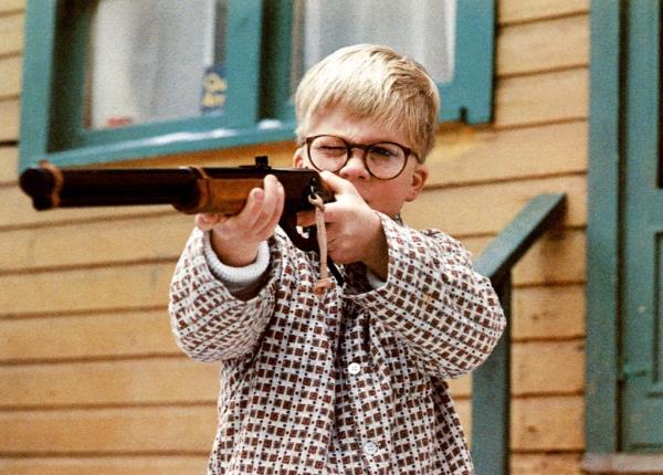 A boy with glasses holding a gun. 