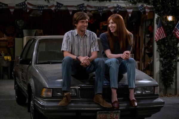 Topher Grace as Eric Forman, Laura Prepon as Do<em></em>nna Pinciotti smiling together on a car. 