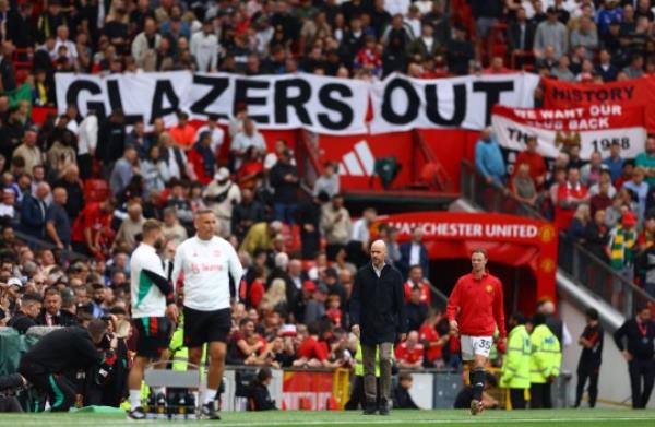 Soccer Football - Premier League - Manchester United v Brighton & Hove Albion - Old Trafford, Manchester, Britain - September 16, 2023 Manchester United manager Erik ten Hag and Manchester United's Jo<em></em>nny Evan walk to the dugout as fans inside the stadium display a Glazers Out banner REUTERS/Molly Darlington NO USE WITH UNAUTHORIZED AUDIO, VIDEO, DATA, FIXTURE LISTS, CLUB/LEAGUE LOGOS OR 'LIVE' SERVICES. o<em></em>nLINE IN-MATCH USE LIMITED TO 45 IMAGES, NO VIDEO EMULATION. NO USE IN BETTING, GAMES OR SINGLE CLUB/LEAGUE/PLAYER PUBLICATIONS.