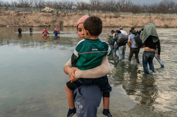 A migrant holds a young child as the two cross the Rio Grande to the US border on Dec. 21, 2023.