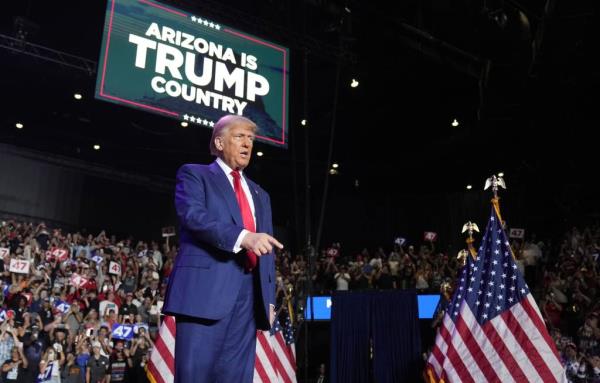 Former President Do<em></em>nald Trump leading a campaign rally at Mullett Arena at ASU in Tempe on Oct. 24, 2024, surrounded by flags and a large crowd.