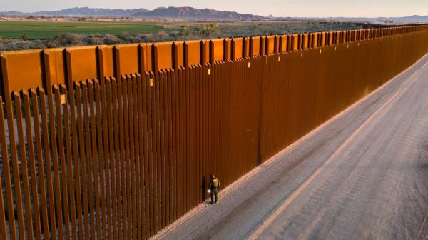 In an aerial view, a U.S. Border Patrol agent searches for immigrant footprints while looking through the U.S.-Mexico border fence on March 9, 2024 in Yuma, Arizona