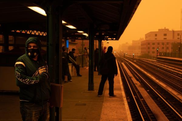 Bronx subway riders wait for a train in the haze of wildfire smoke that drifted down from Canada.