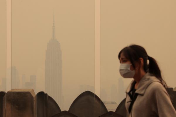 A person wears a mask as the Empire State Building is enveloped by smoke.