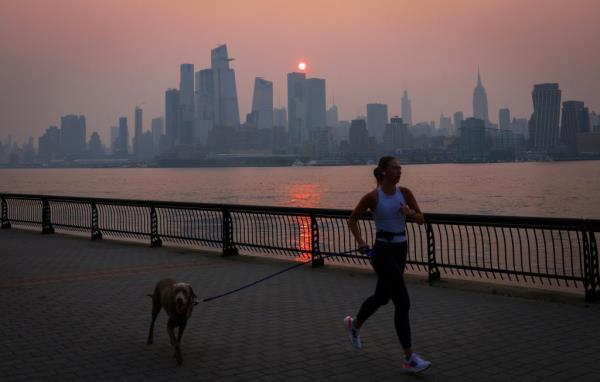 A lone person jogs with a dog along the Hudson River shortly after sunrise Wednesday. Smoke inhalation in pets can be as serious a problem as it is for humans, experts warn.