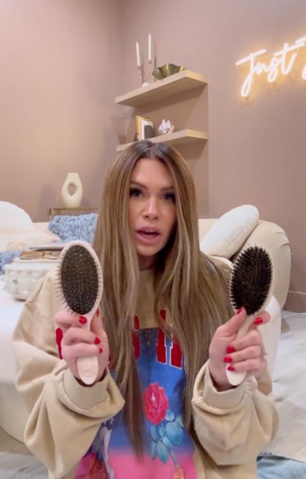 A woman holding two brushes, associated with 'Utah curls' co<em></em>ncept from 'The Secret Lives of Mormon Wives' series on TikTok by Jessi Ngatikaura