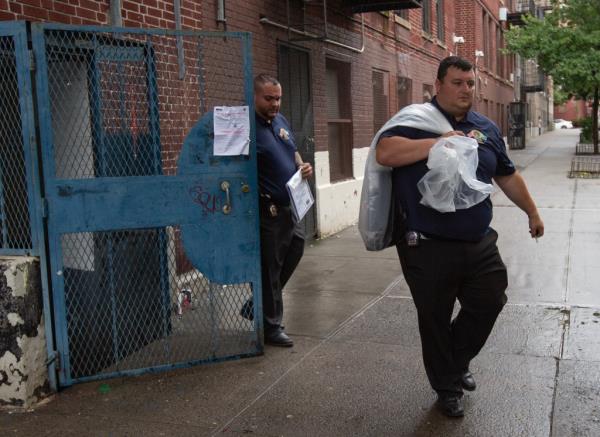 NYPD officer carries a bag out of Mendez's Bronx apartment