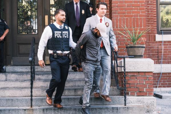 Carlisto Acevedo Brito in handcuffs being walked out of the 52nd NYPD precinct