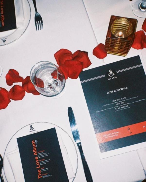 Table setting with rose petals, glasses, a cocktail menu and promo card for 