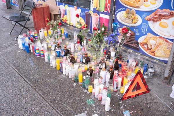 A shooting memorial of flowers and novina candles outside a deli.