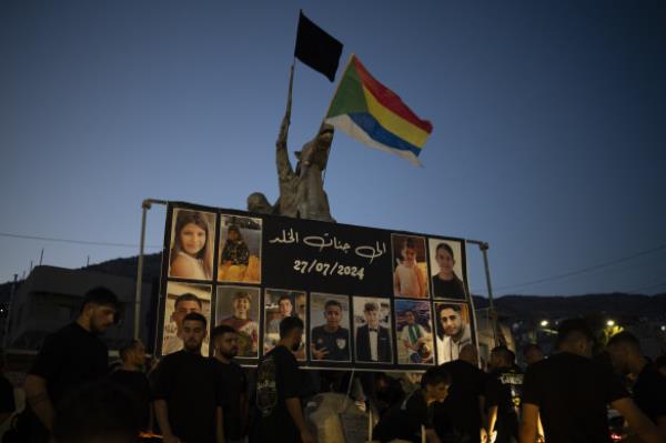 Photos of the children and teens killed in a rocket strike at a soccer field, are displayed at a rounda<em></em>bout as people light candles in their memories, at the village of Majdal Shams.