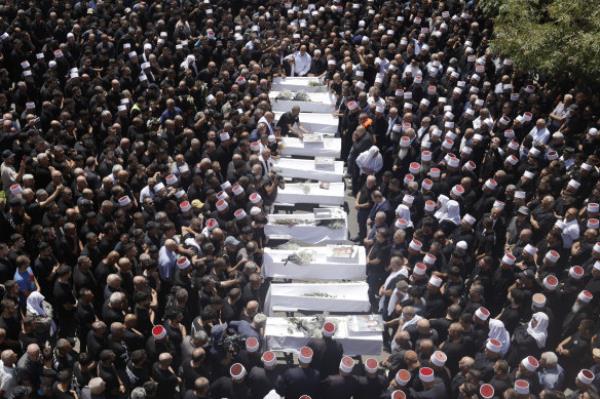 Mourners attend a funeral held for 10 of the victims of yesterday’s rocket attack in Majdal Shams, Golan Heights. 