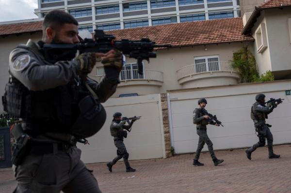 Israeli security forces search for assailants near the scene of a deadly car-ramming and stabbing attack at a bus stop, in Ra'anana, Israel, Monday, Jan. 15, 2024. 