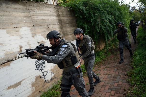 Israeli security forces search for assailants near the scene of a deadly car-ramming and stabbing attack at a bus stop, in Ra'anana, Israel, Monday, Jan. 15, 2024. 