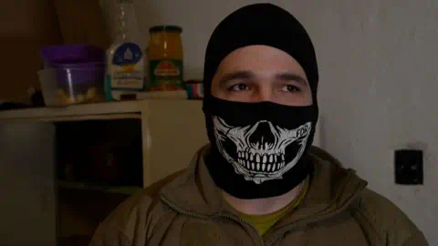 Surt, a 31-year-old commander, hides his face with a balaclava